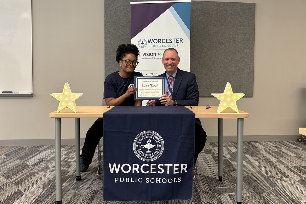 A woman and a man smile while holding a "Certificate of Intention" from Worcester Public Schools.
