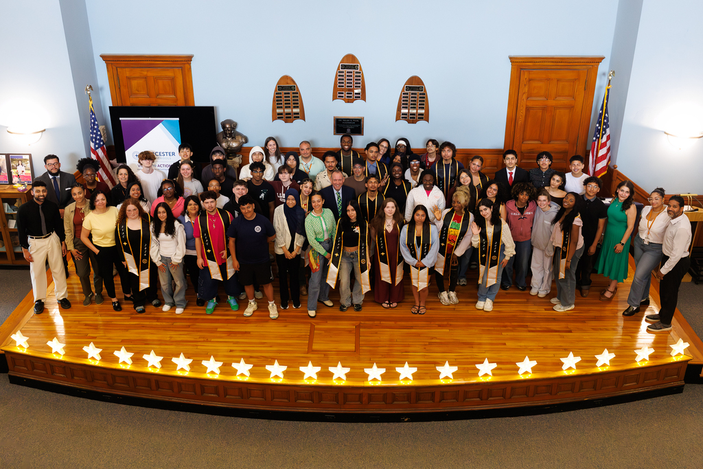 A large group of students and staff take a photo on stage.