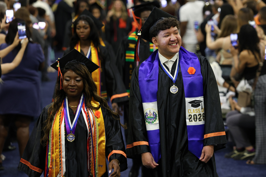 A student smiles as they walk to the stage during high school graduation.
