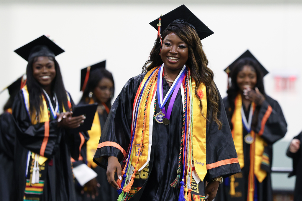A student smiles while walking across the stage at graduation.