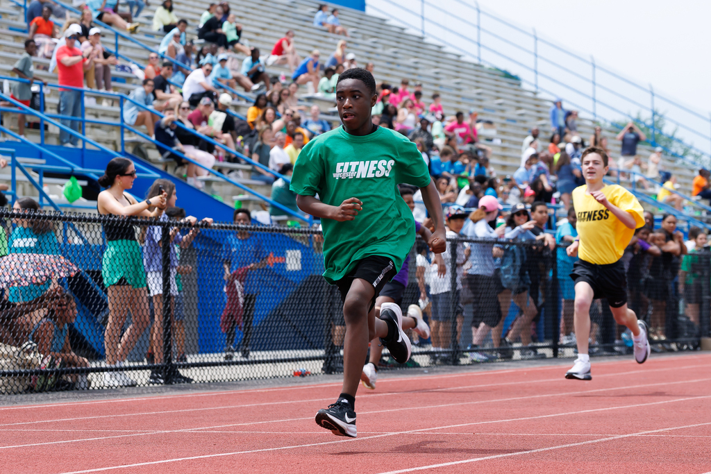 A student runs on the track during a race with another closely behind.