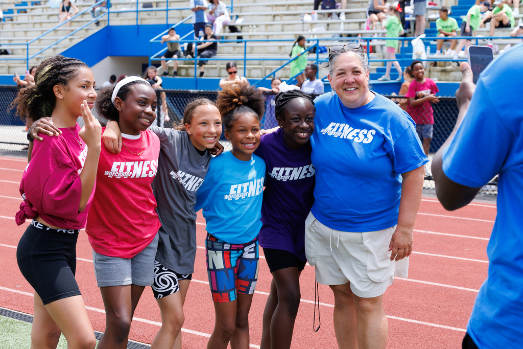 Five students stand alongside a teacher, smiling for a photo.