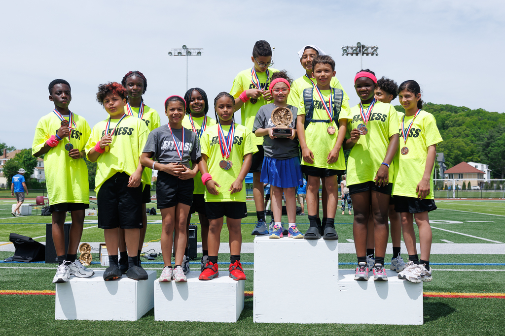 A group of students stand on the podium while holding a trophy.
