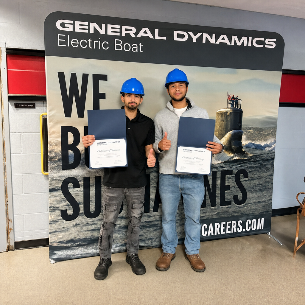 Two Worcester Technical High School students receiving their hard hats for signing day at General Dynamics