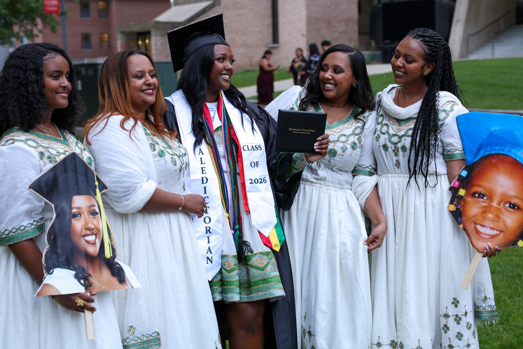 A family of five stand together and smile.