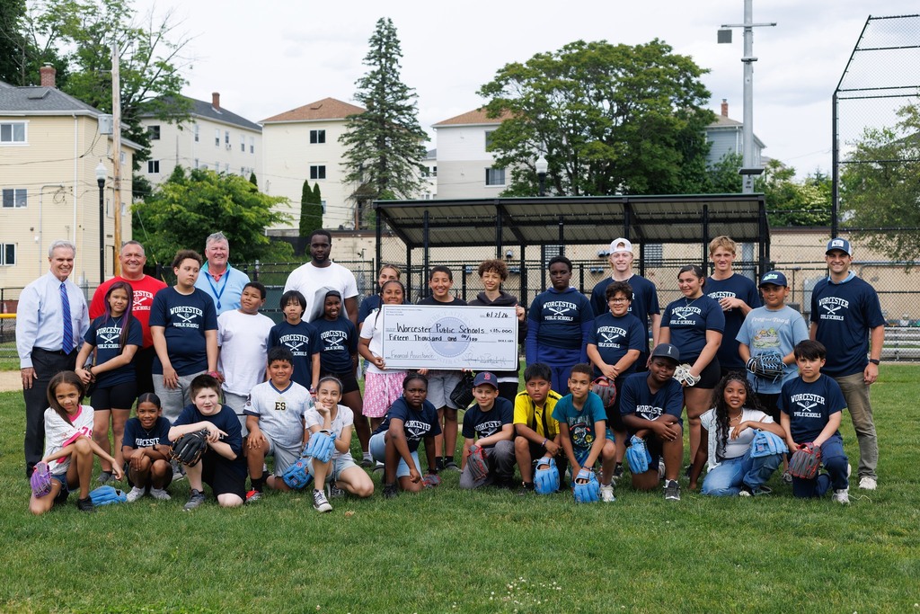 Students and adults stand together for a group photo while holding a donated check.