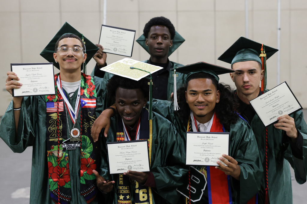 Five high school graduates hold up their newly aquired diplomas.