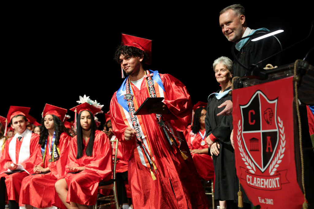A high school graduate accepts their diploma while walking across stage.