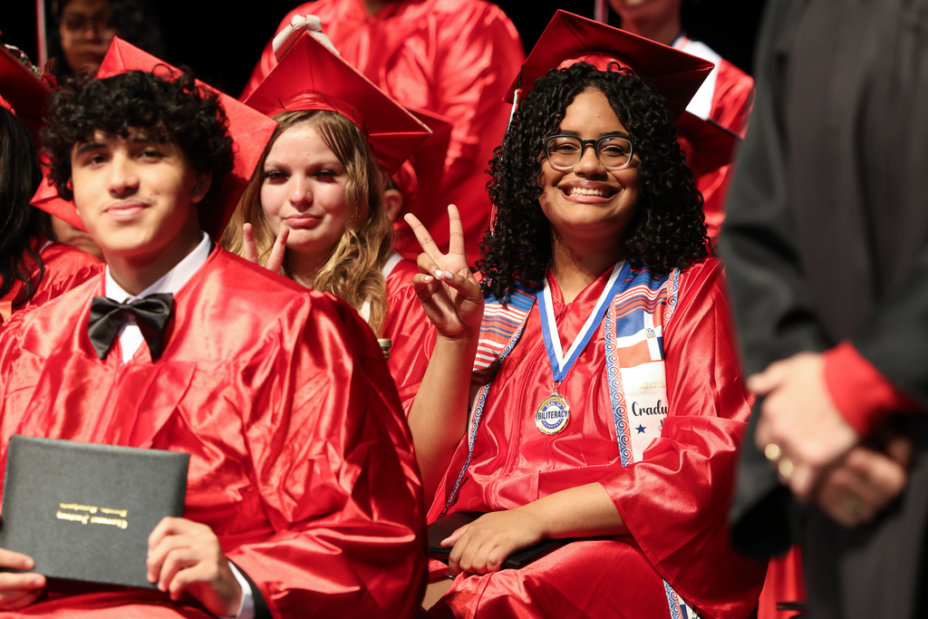 A student gives the peace sign during graduation.