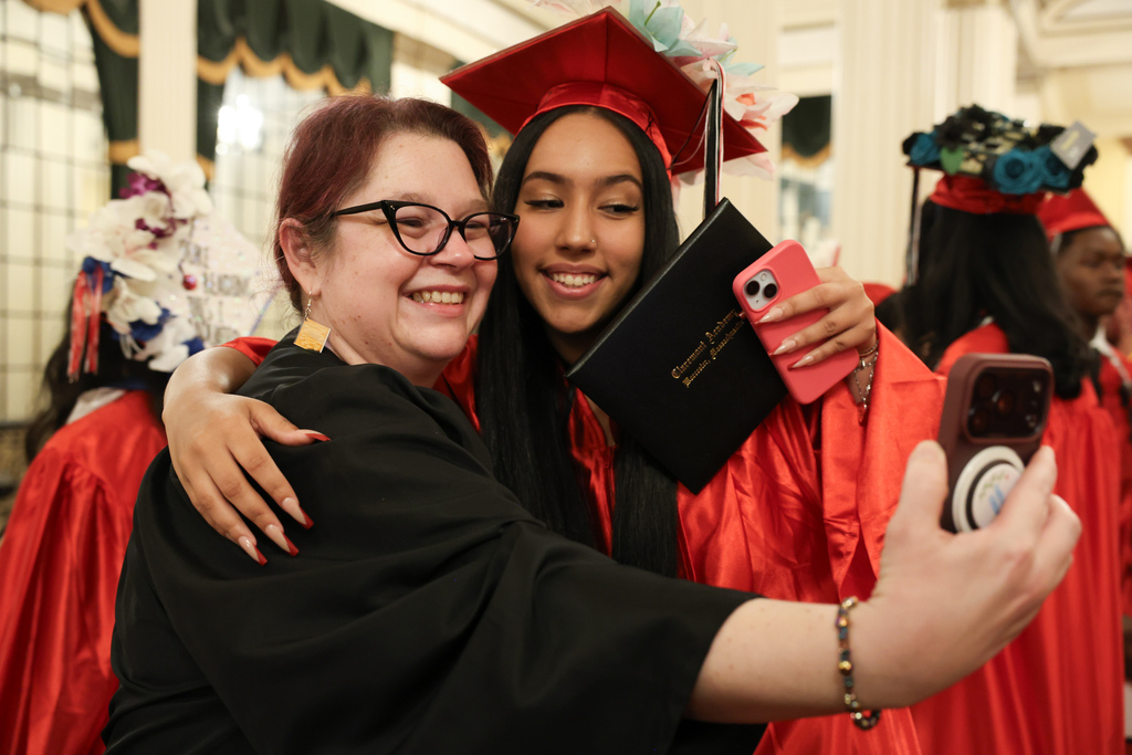 A student and teacher take a selfie together following high school graduation.