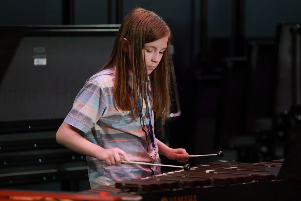 A student is focused while playing the xylophone.