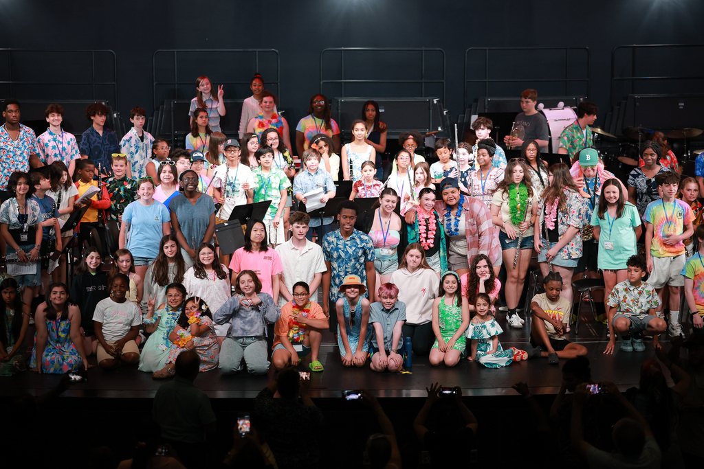 A large group of students stand together on stage.