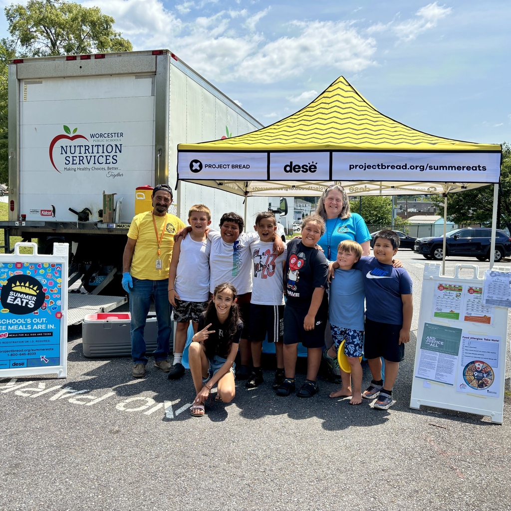 A group of children and adults stand in front of a truck and a yellow tent for Project Bread's Summer Eats program.