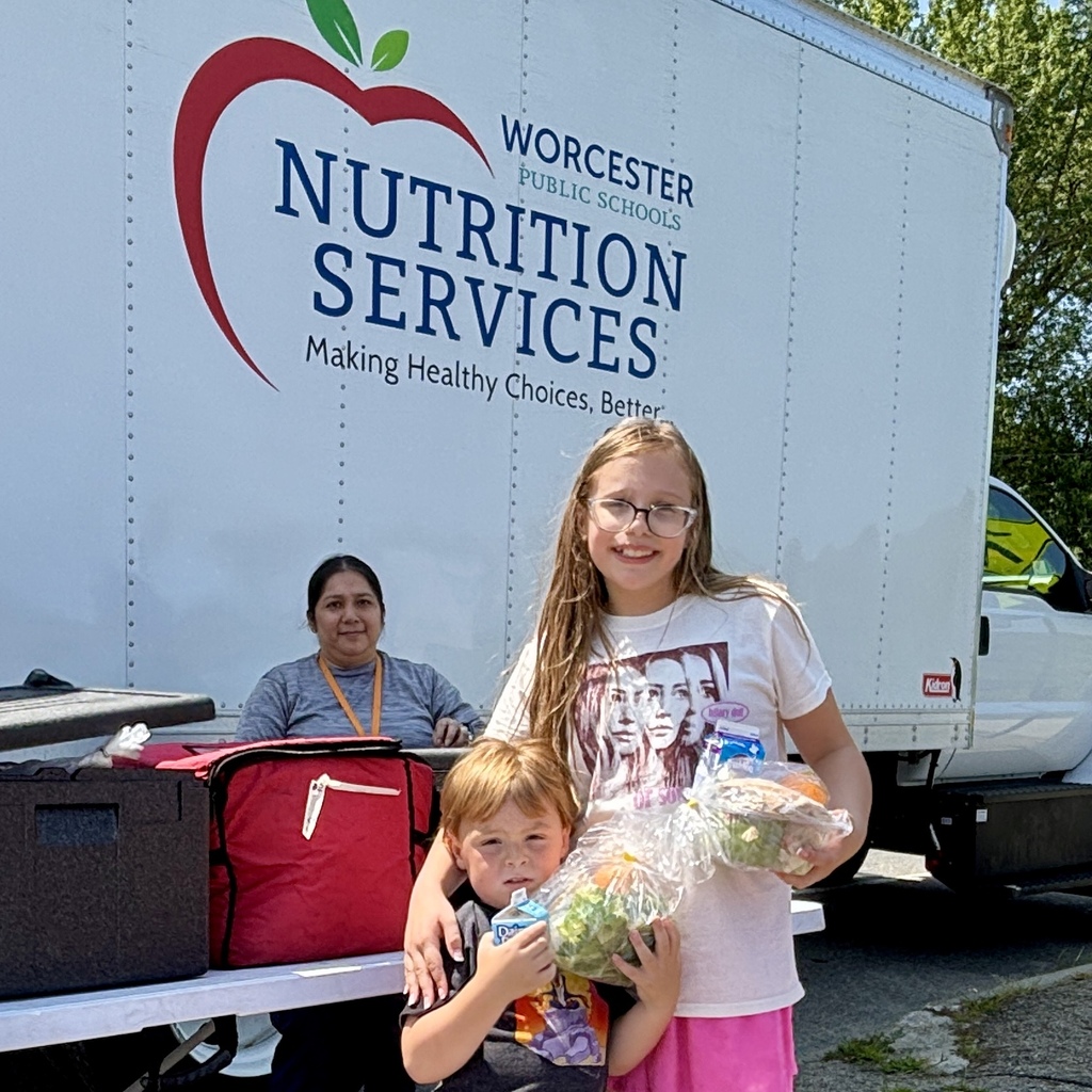 Two children hold bags of groceries in front of a Worcester Public Schools Nutrition Services truck.