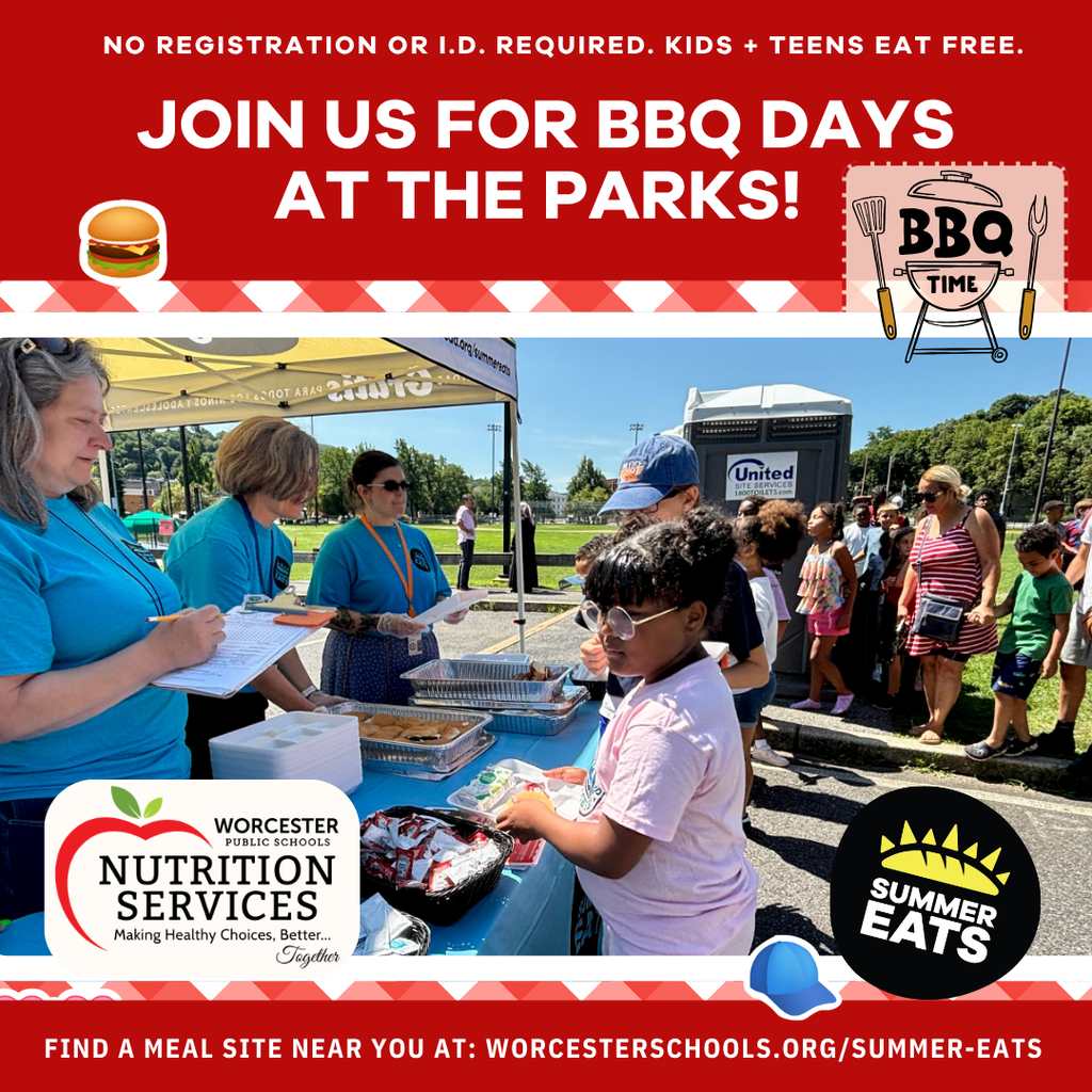 Children and adults line up at a table for free BBQ meals at a park event, with volunteers serving food.