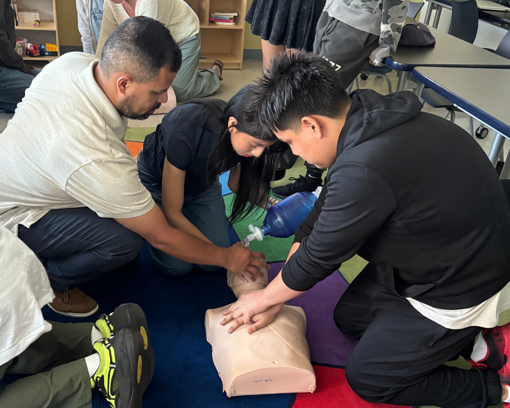 Students and an instructor practice CPR in a classroom setting.