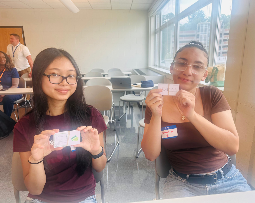 Students hold up their own business cards.
