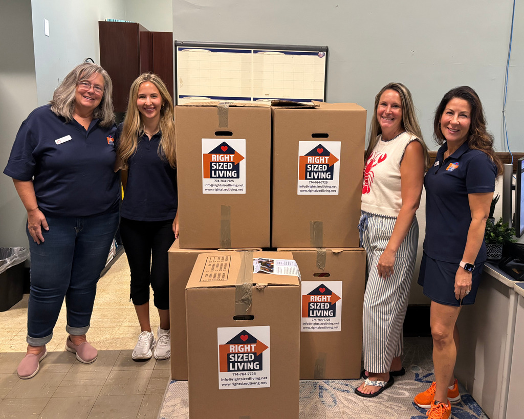 Four adults stand beside a large school supplies donation.