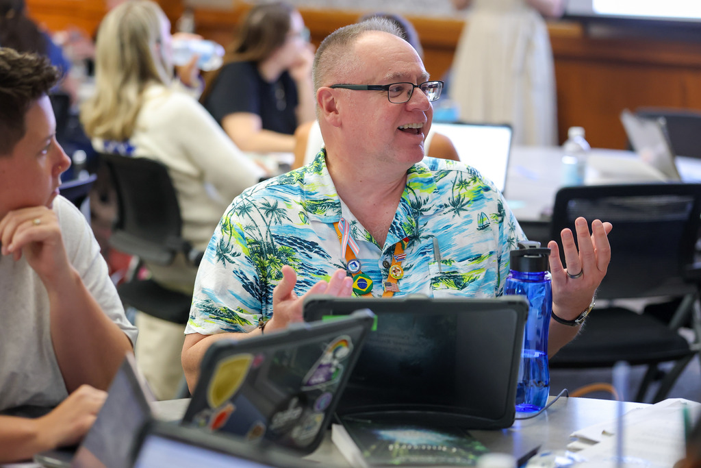 A teacher smiles as he talks to colleagues.