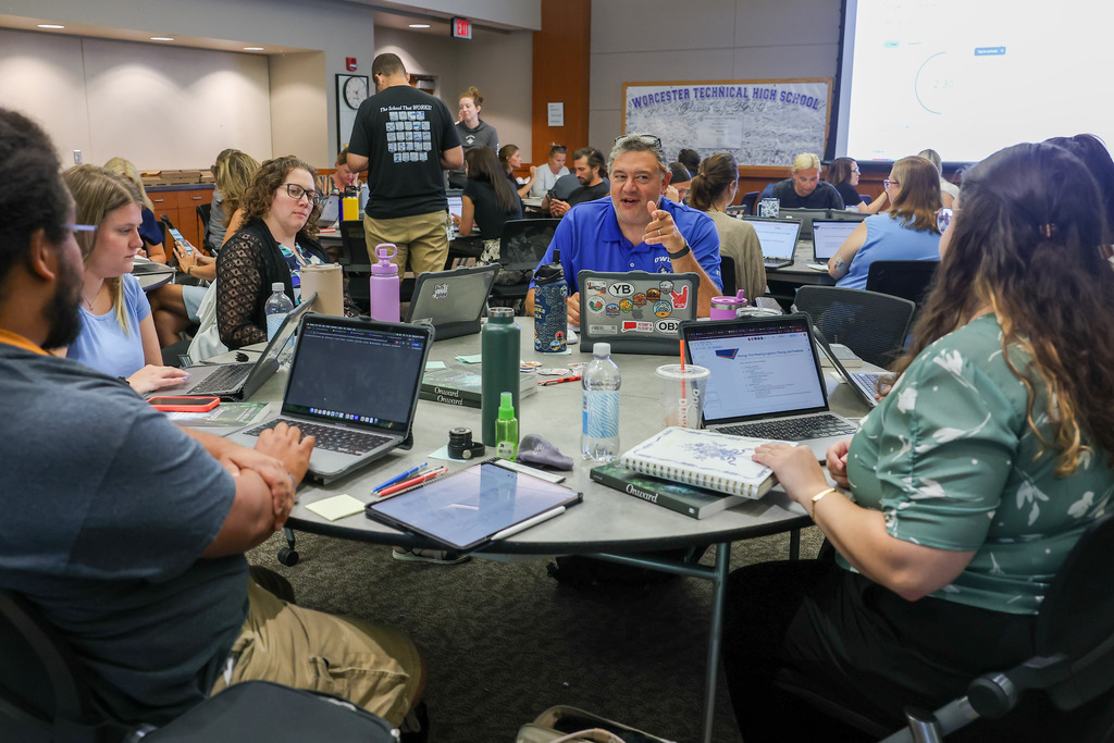 A table of teachers have a conversation around a table.