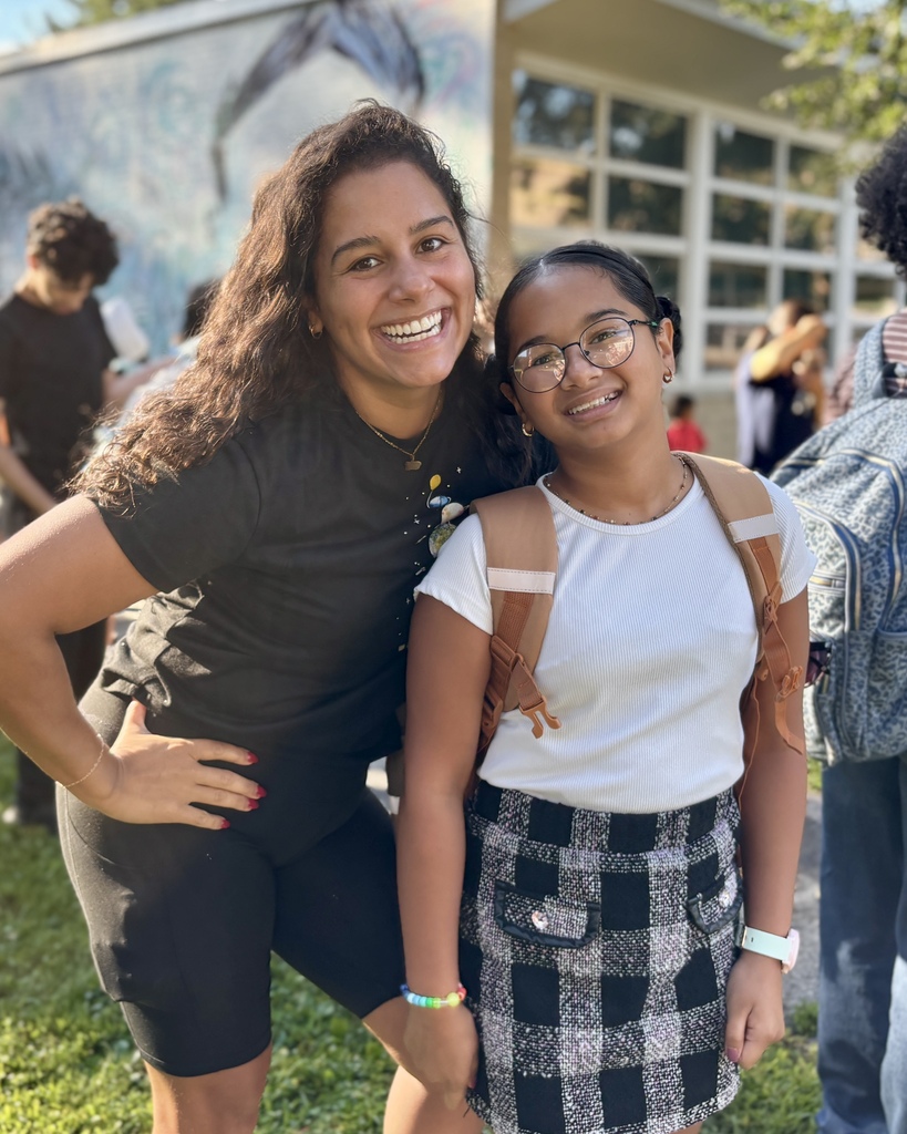 A mother stands alongside her daughter on the first day of school.