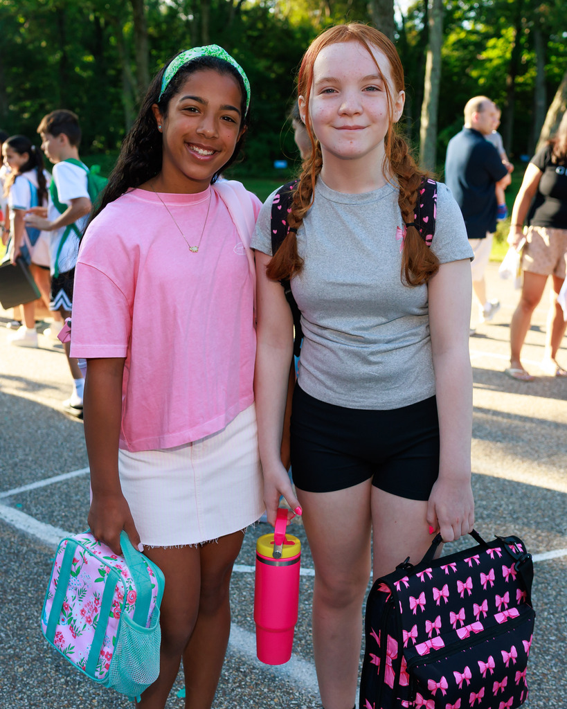 Two friends stand side by side on the first day of elementary school.