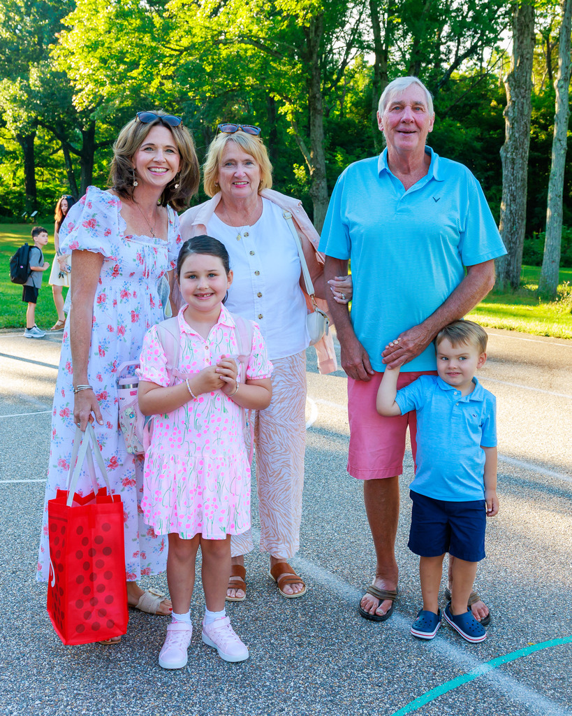 Two young students stand alongside a mother and grandparents.