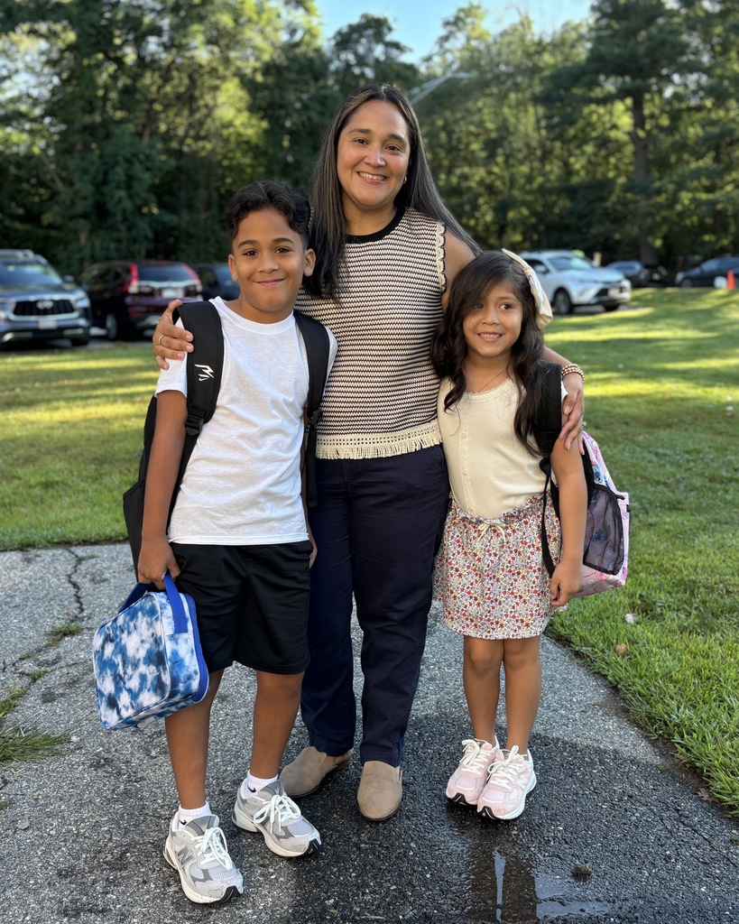 A mother stands with her two children on the first day of elementary school.