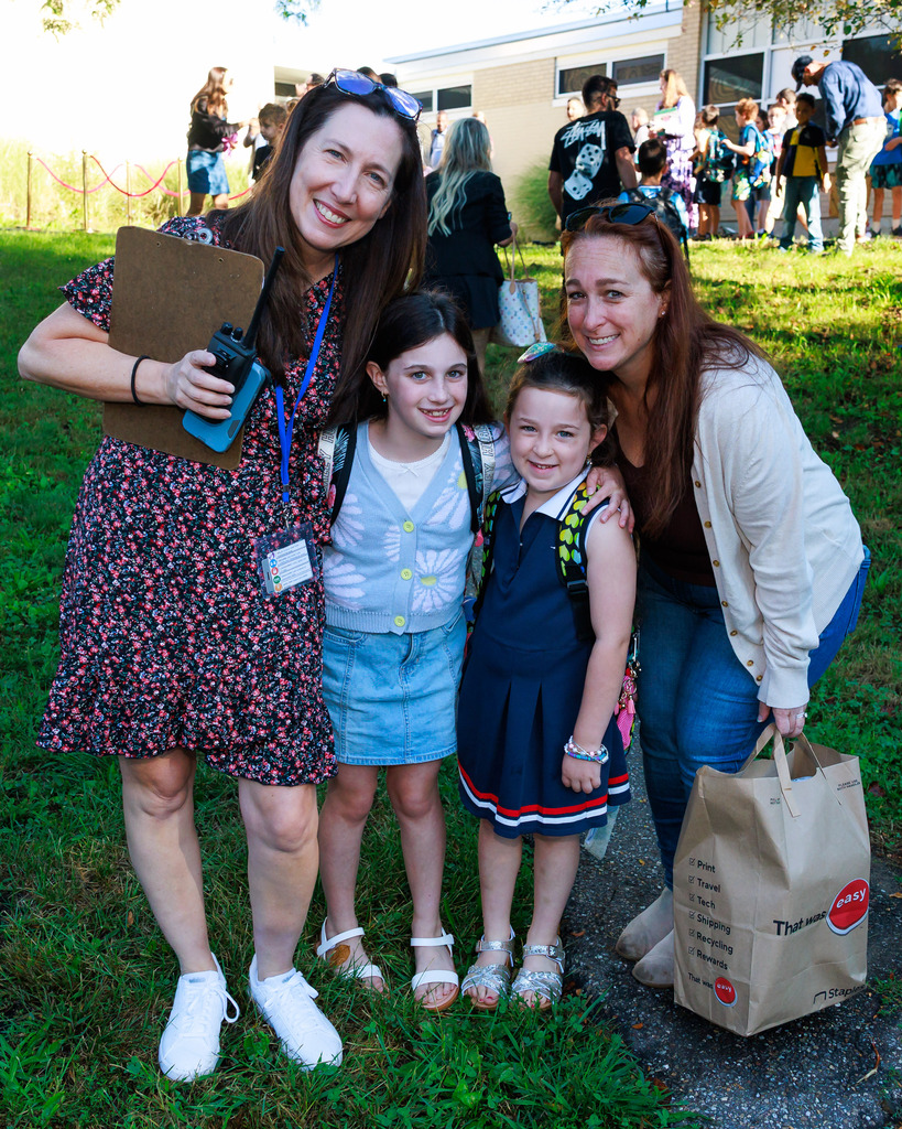 Principal Colleen Dyer stands with two young students and a mother.