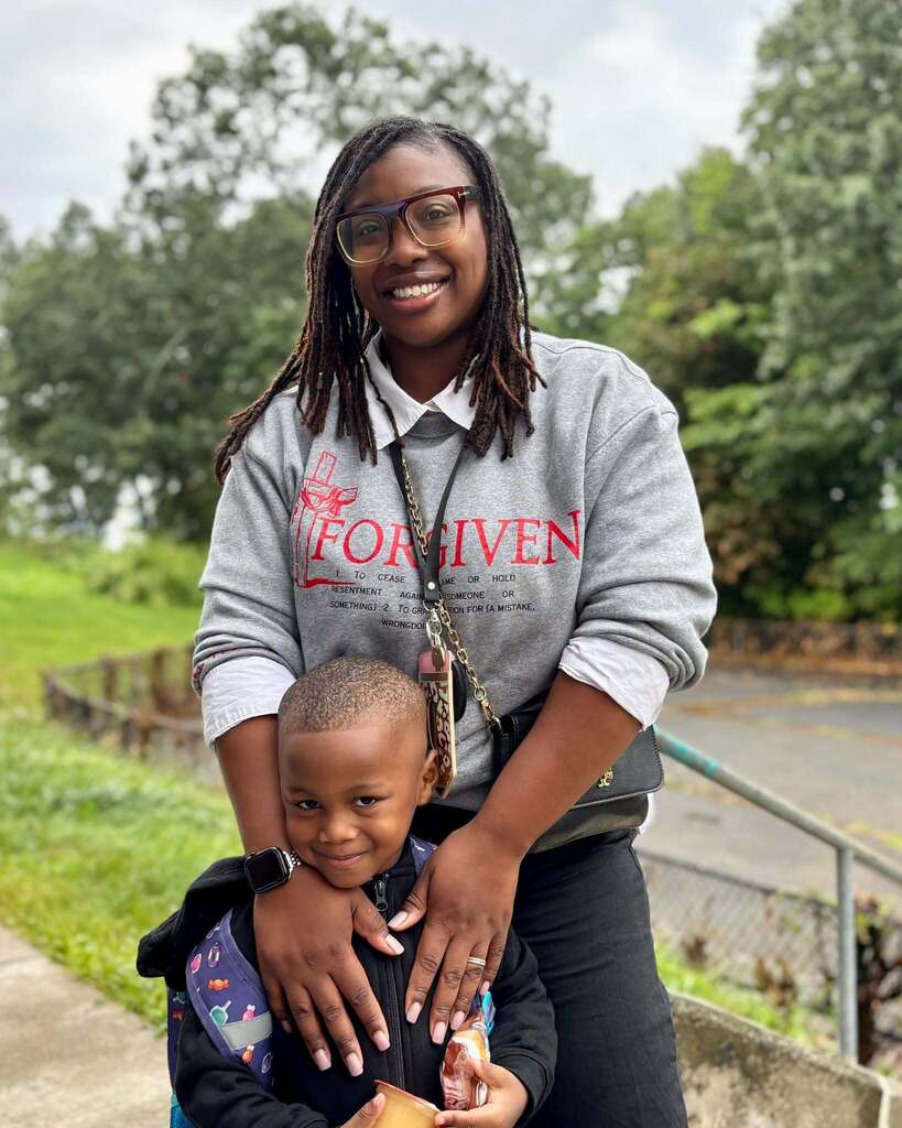 A student and his mother stand together on the first day of Pre-K and Kindergarten.