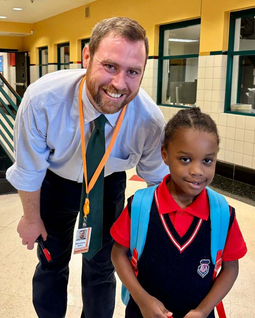 A principal stands with a young student on the first day of Pre-K and Kindergarten.