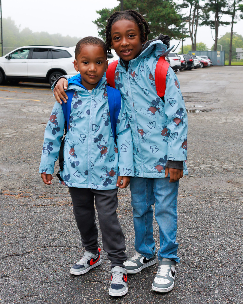 Two young students stand together on the first day or pre-k and kindergarten.