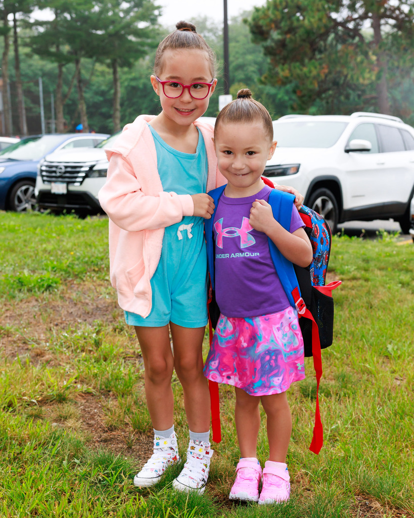 Two young students stand together on the first day or pre-k and kindergarten.