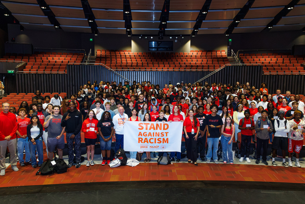South High students stand with WPS leadership holding the Stand Against Racism banner.