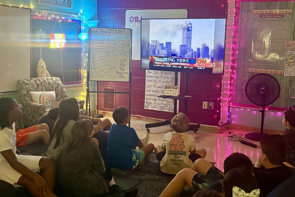 Students watch a recording of a news broadcast from September 11, 2001.