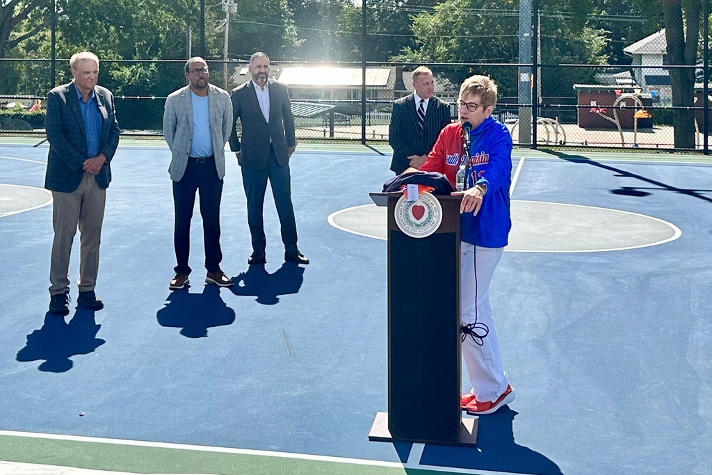 Nancy Mayer Bates speaks at the podium during a court dedication ceremony.