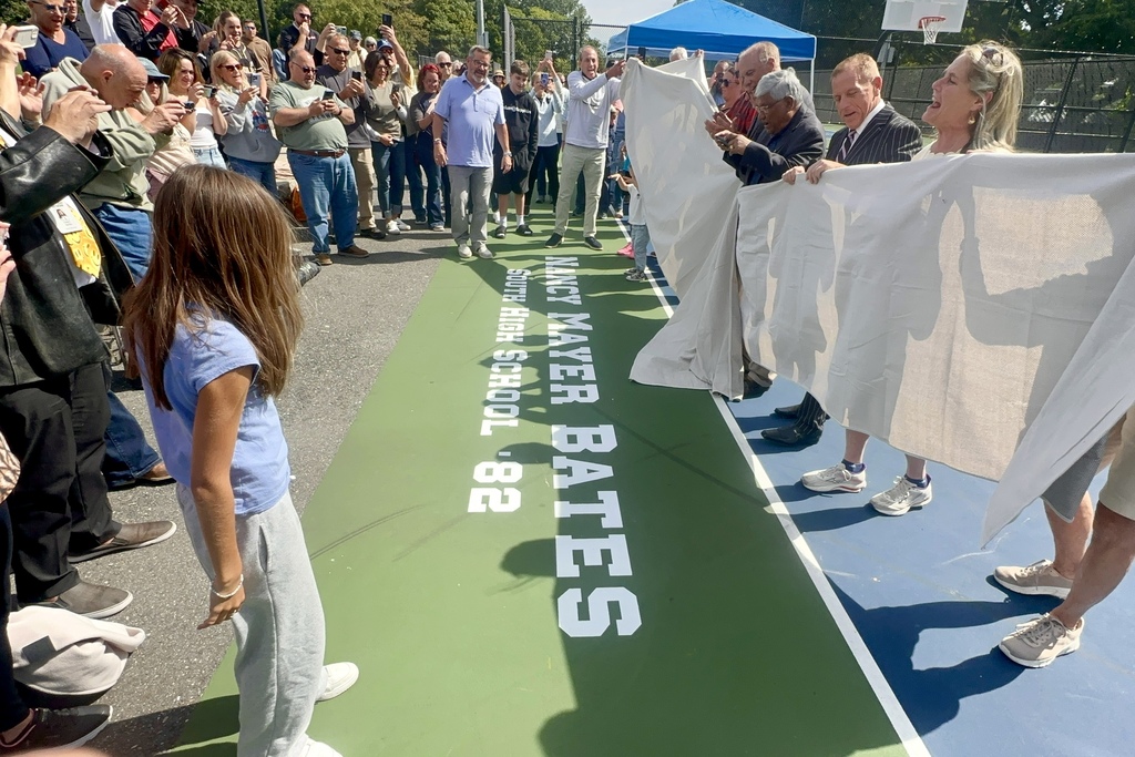A tarp is lifted to unveil the Nancy Mayer Bates court dedication.