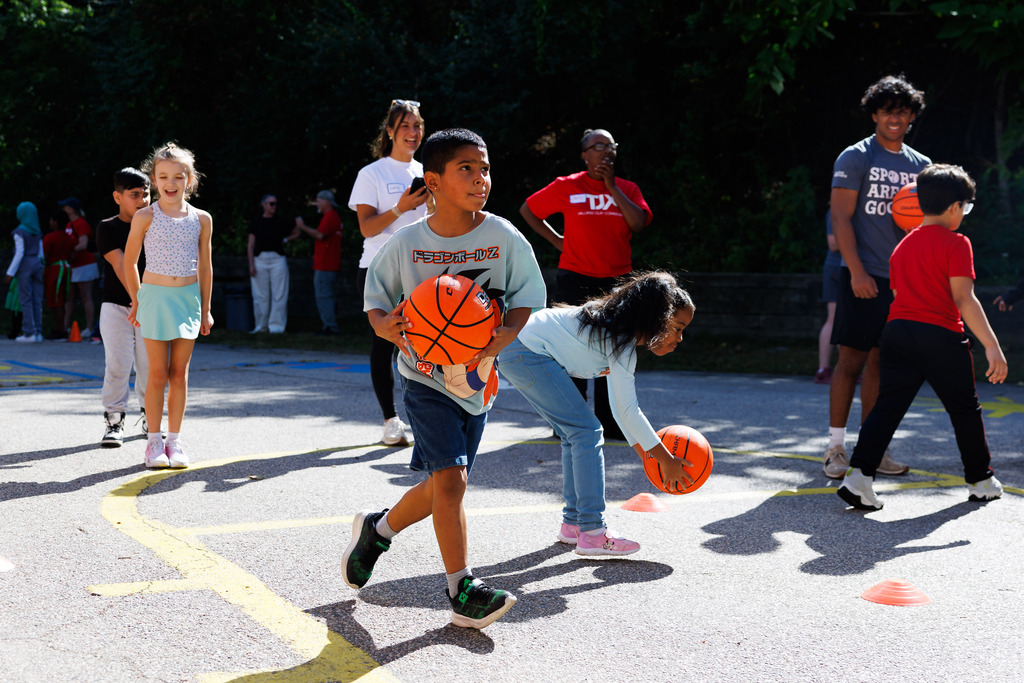 A student dribbles toward the hoop while playing outside.
