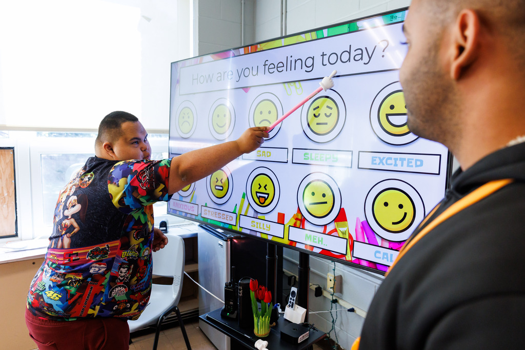 A student uses a pointer to bring attention to the words "How are you feeling today"