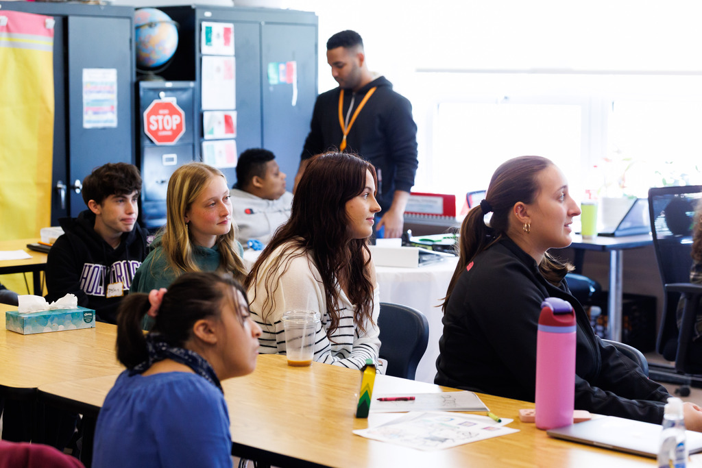 Student helpers from Holy Cross look on during a class.