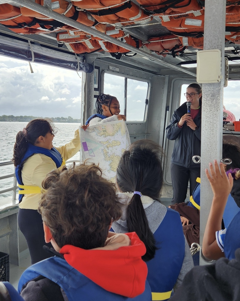 Students participate in a learning activity while on a boat.