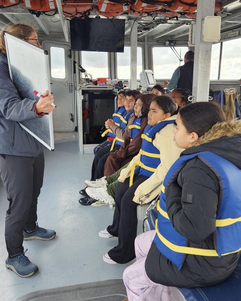 Students participate in a learning activity while on a boat.