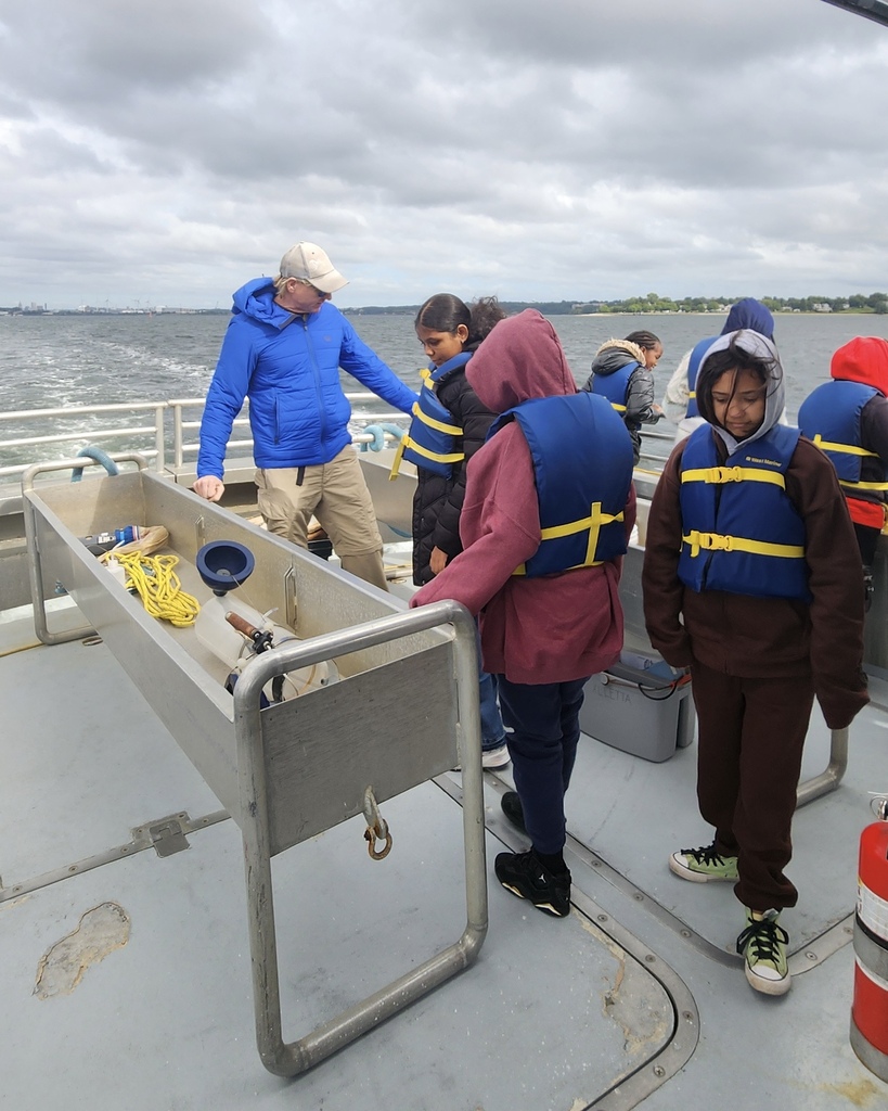 Students participate in a learning activity while on a boat.