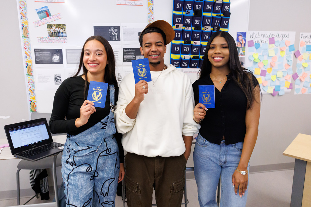 Students hold up passports while working on a class activity.