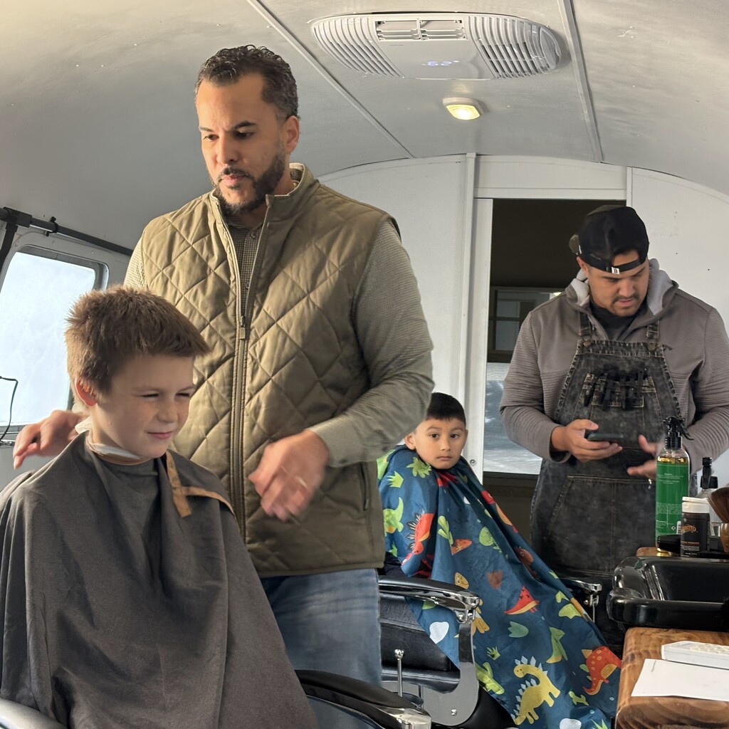 A barber cuts a young boy's hair inside a mobile salon trailer.