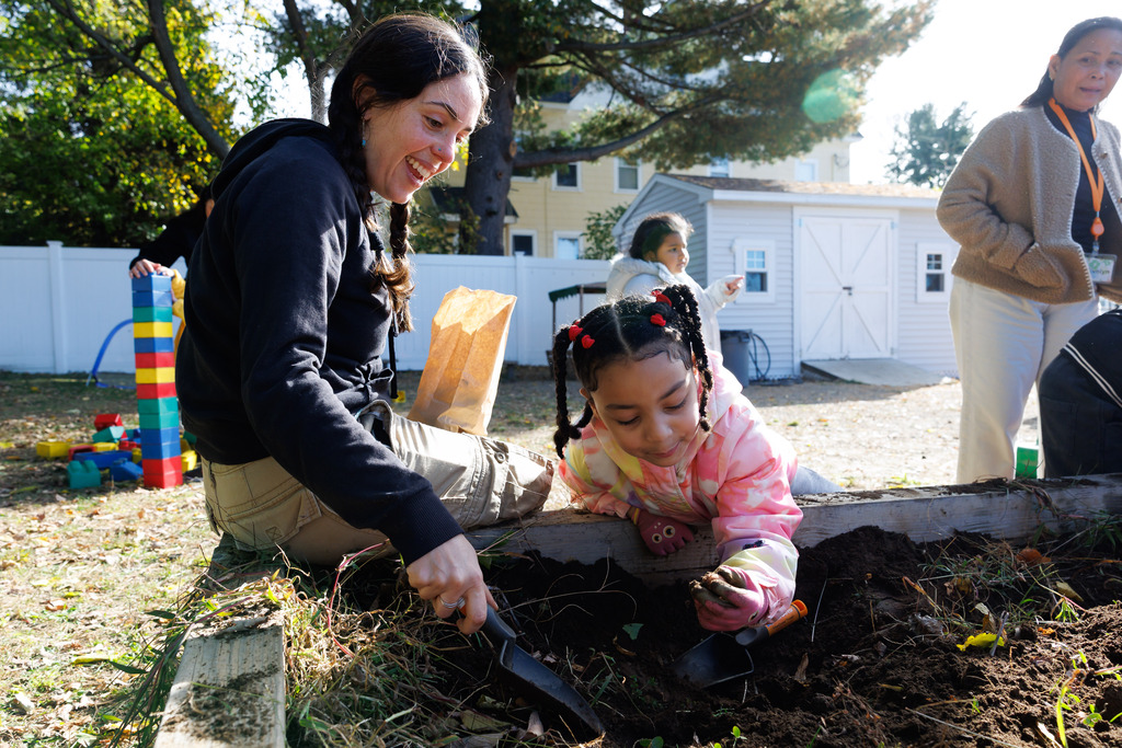 A student finds a potato in the garden while an adult watches.