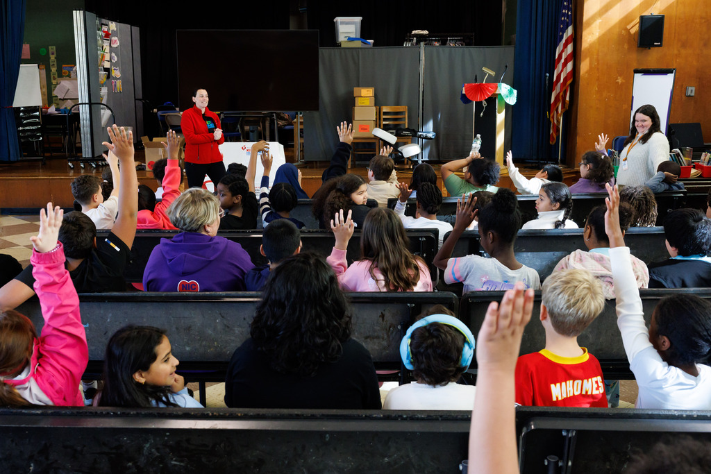 Students raise their hands during a presentation.