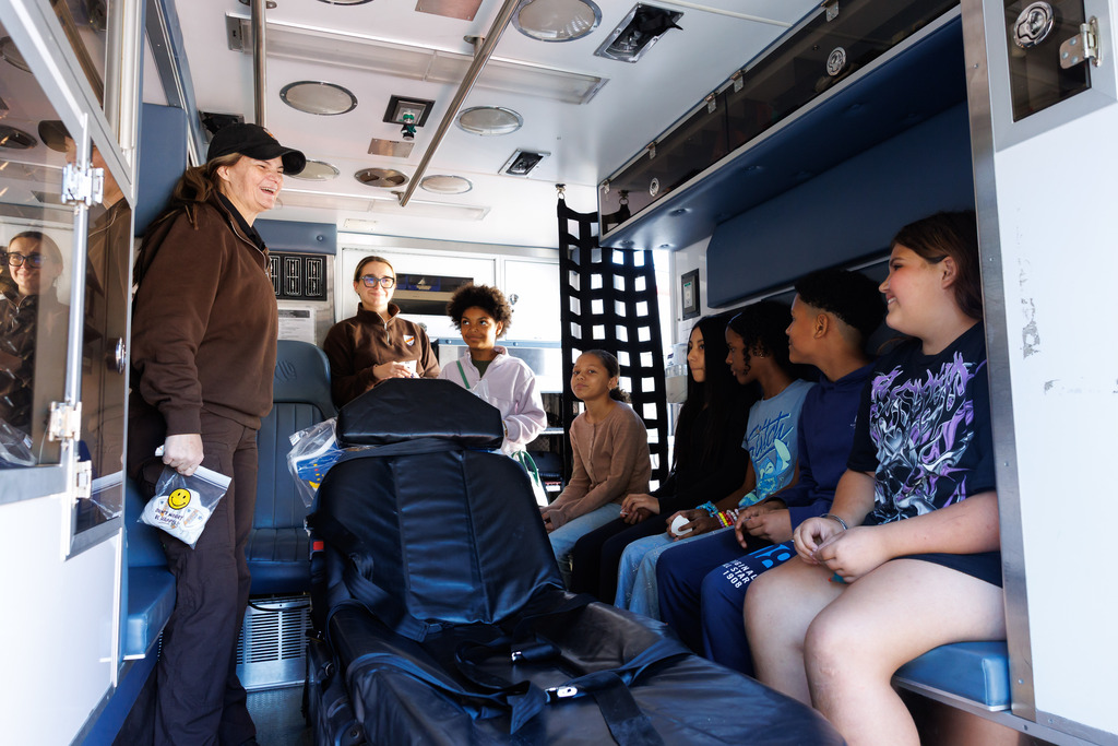 An EMS worker interacts with students inside of an ambulance.