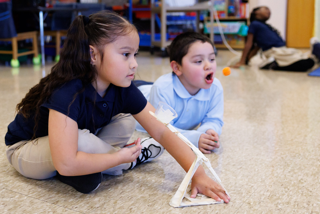 Students use a catapult to launch candy pumpkins.
