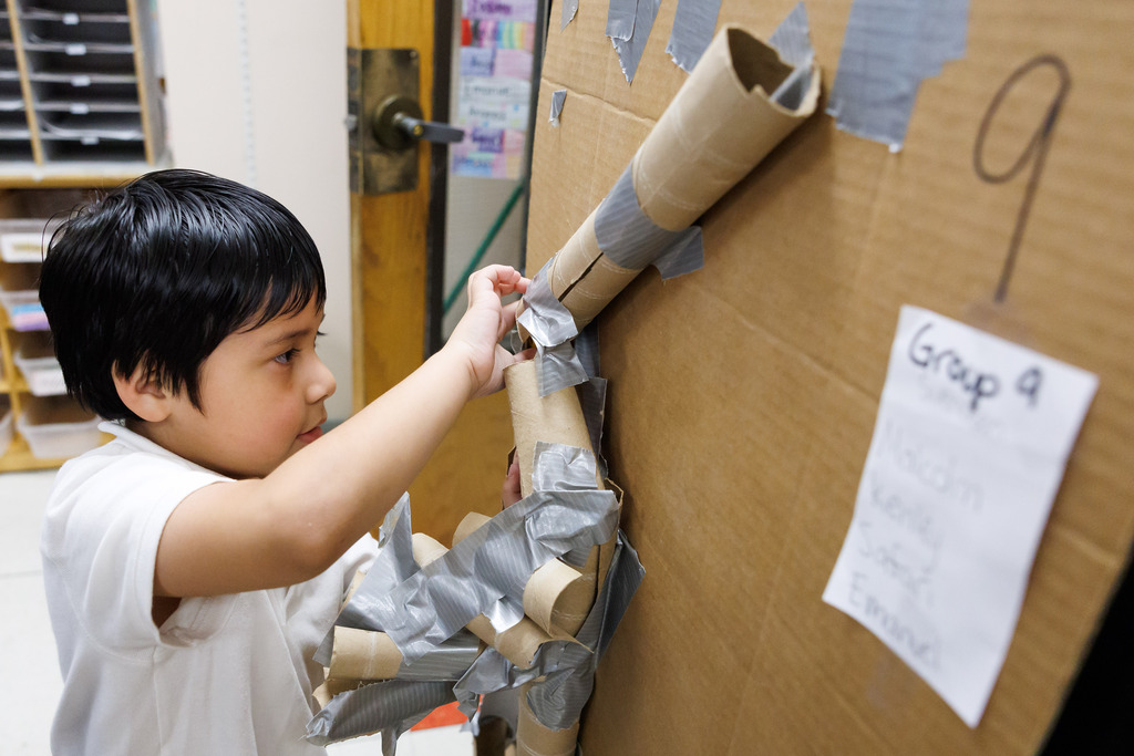 A student retrieves their marble from a tube-system during a STEM week activity.